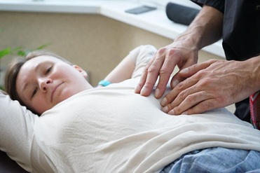 Professional mobile massage therapist providing remedial abdominal massage for menstrual pain relief in Sydney home setting